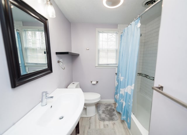 full bathroom with shower / bathtub combination with curtain, sink, hardwood / wood-style flooring, and toilet