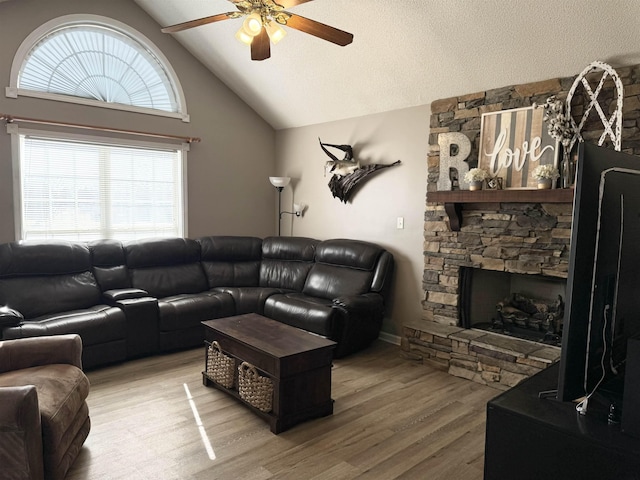 living room with lofted ceiling, a textured ceiling, ceiling fan, a fireplace, and hardwood / wood-style floors