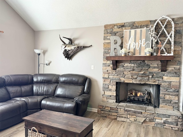 living room featuring a fireplace, light hardwood / wood-style floors, a textured ceiling, and vaulted ceiling