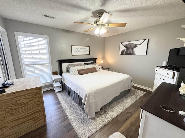 bedroom with dark hardwood / wood-style flooring, ceiling fan, and a textured ceiling