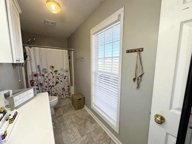 bathroom with toilet, shower / tub combo, and a textured ceiling