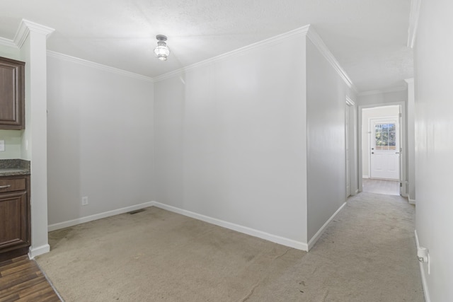 unfurnished dining area with light carpet, ornamental molding, and a textured ceiling