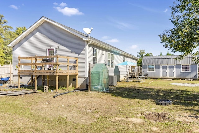 back of property with a wooden deck, a yard, central AC unit, and a storage shed