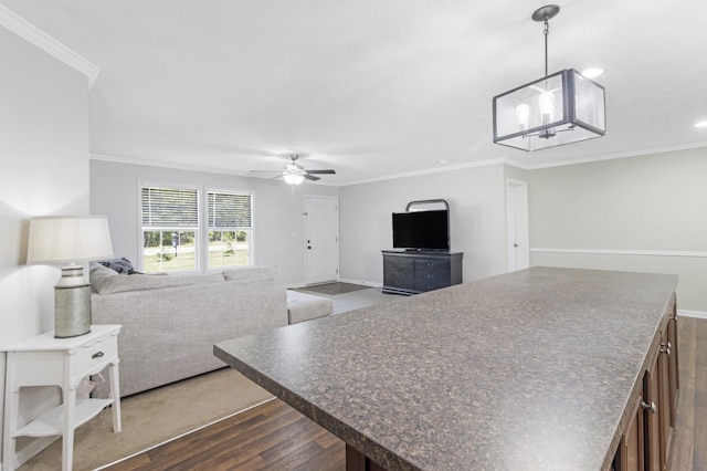 kitchen with hanging light fixtures, ornamental molding, dark hardwood / wood-style floors, and ceiling fan with notable chandelier