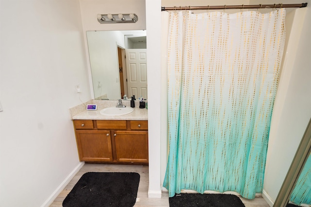 bathroom featuring walk in shower, vanity, and wood-type flooring