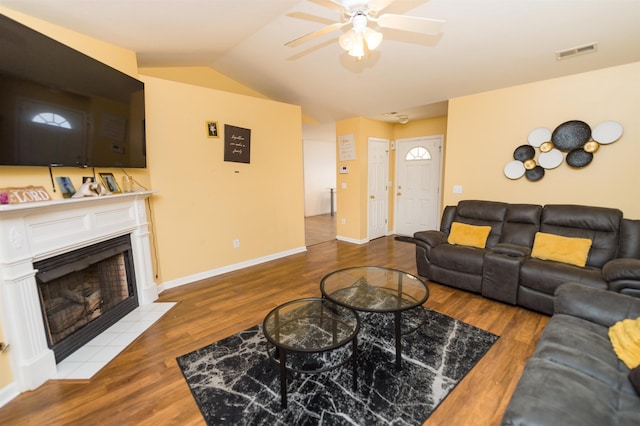 living room with a tiled fireplace, lofted ceiling, hardwood / wood-style floors, and ceiling fan