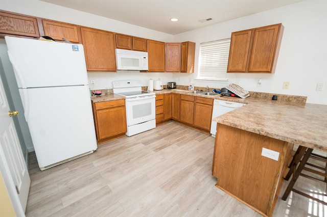 kitchen with sink, kitchen peninsula, white appliances, and light hardwood / wood-style flooring