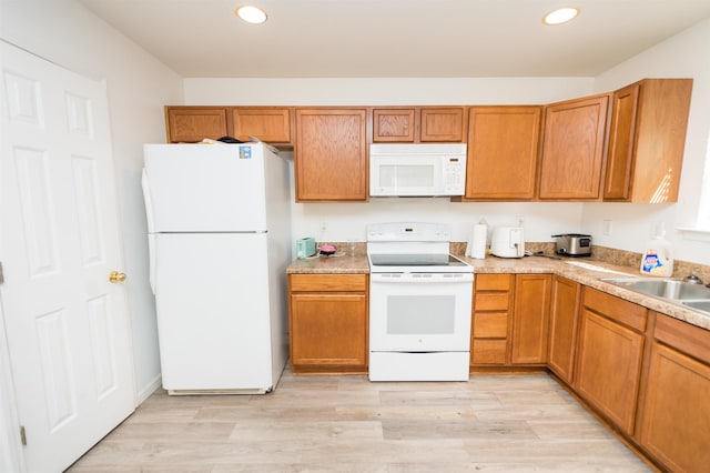 kitchen with white appliances, sink, and light hardwood / wood-style flooring