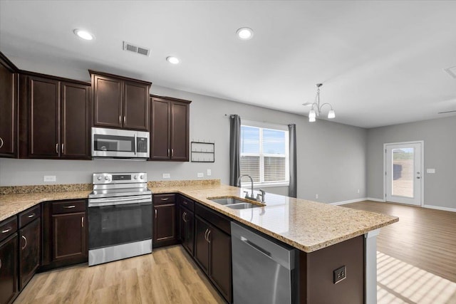 kitchen featuring a wealth of natural light, decorative light fixtures, sink, kitchen peninsula, and stainless steel appliances