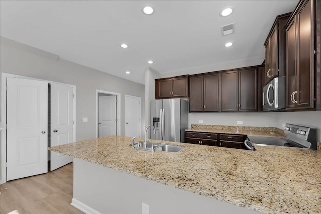 kitchen featuring appliances with stainless steel finishes, light stone countertops, sink, and kitchen peninsula