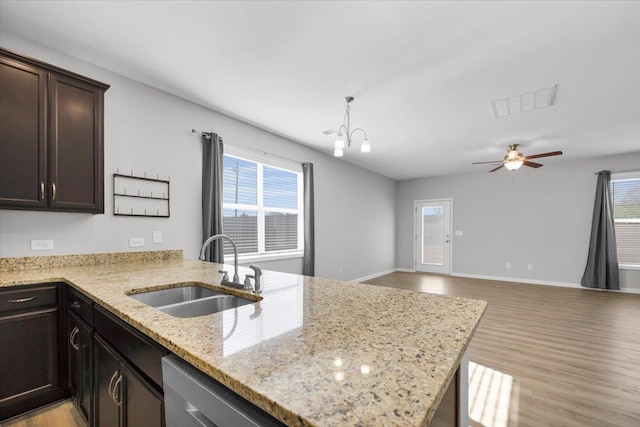 kitchen with sink, light stone countertops, stainless steel dishwasher, kitchen peninsula, and light wood-type flooring