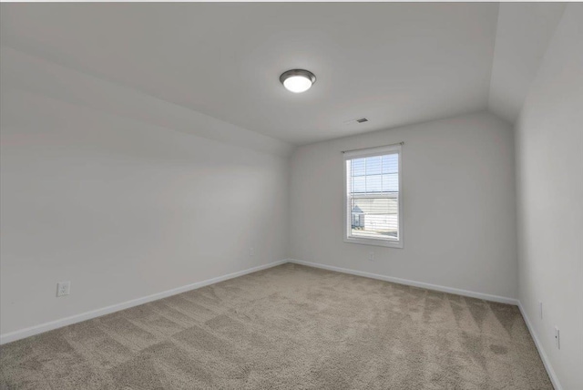 carpeted empty room with lofted ceiling