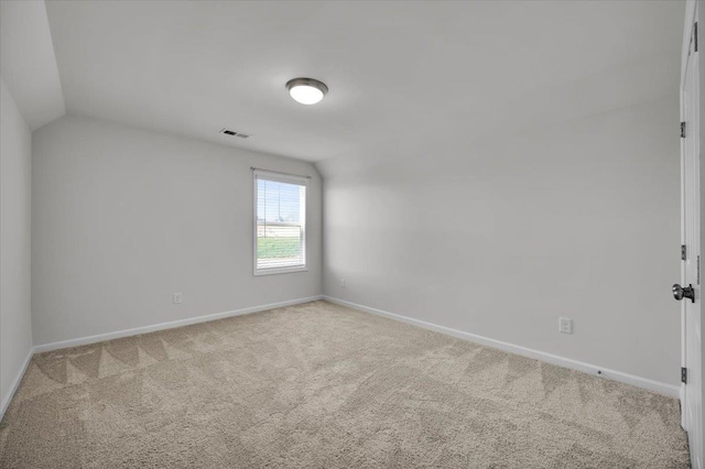 empty room featuring light colored carpet and lofted ceiling