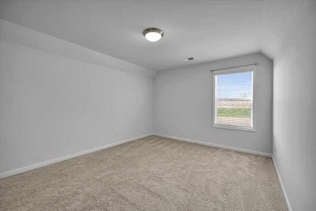 carpeted spare room featuring vaulted ceiling