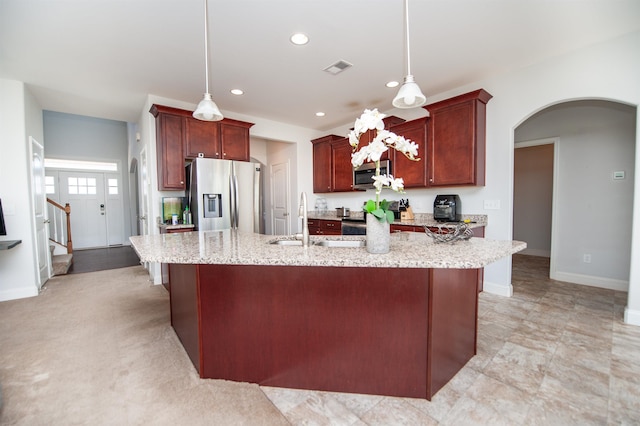 kitchen featuring stainless steel appliances, decorative light fixtures, a kitchen island with sink, and sink