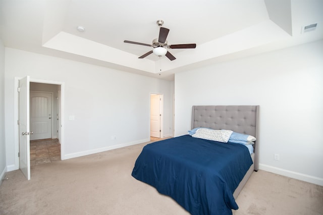 carpeted bedroom featuring ceiling fan and a tray ceiling