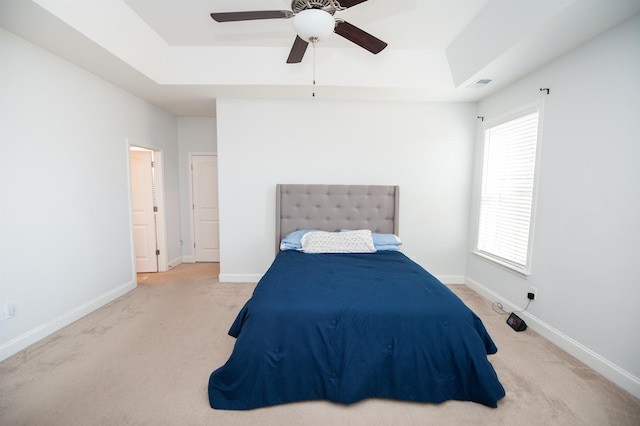 carpeted bedroom featuring a tray ceiling and ceiling fan