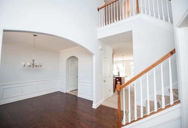 interior space with a notable chandelier, crown molding, wood-type flooring, and a high ceiling