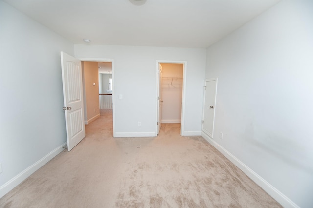 unfurnished bedroom with light colored carpet, a closet, and a walk in closet