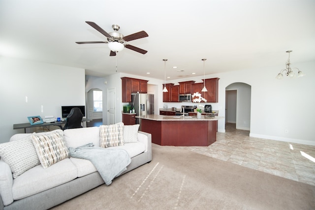 living room with ceiling fan with notable chandelier and sink