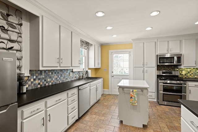 kitchen with stainless steel appliances, white cabinetry, sink, and ornamental molding