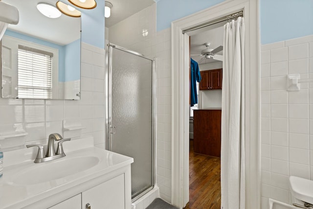 bathroom featuring an enclosed shower, tile walls, vanity, hardwood / wood-style flooring, and ceiling fan