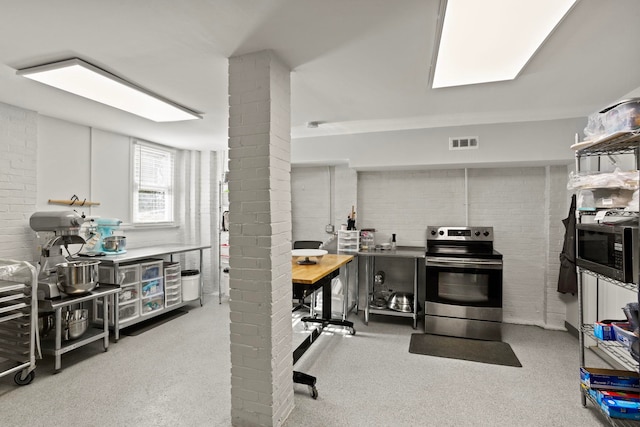 kitchen featuring brick wall and appliances with stainless steel finishes