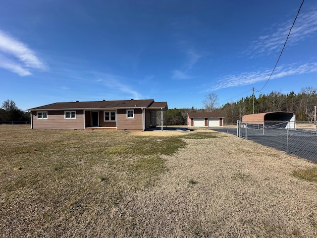 back of property with a garage, a carport, an outbuilding, and a lawn