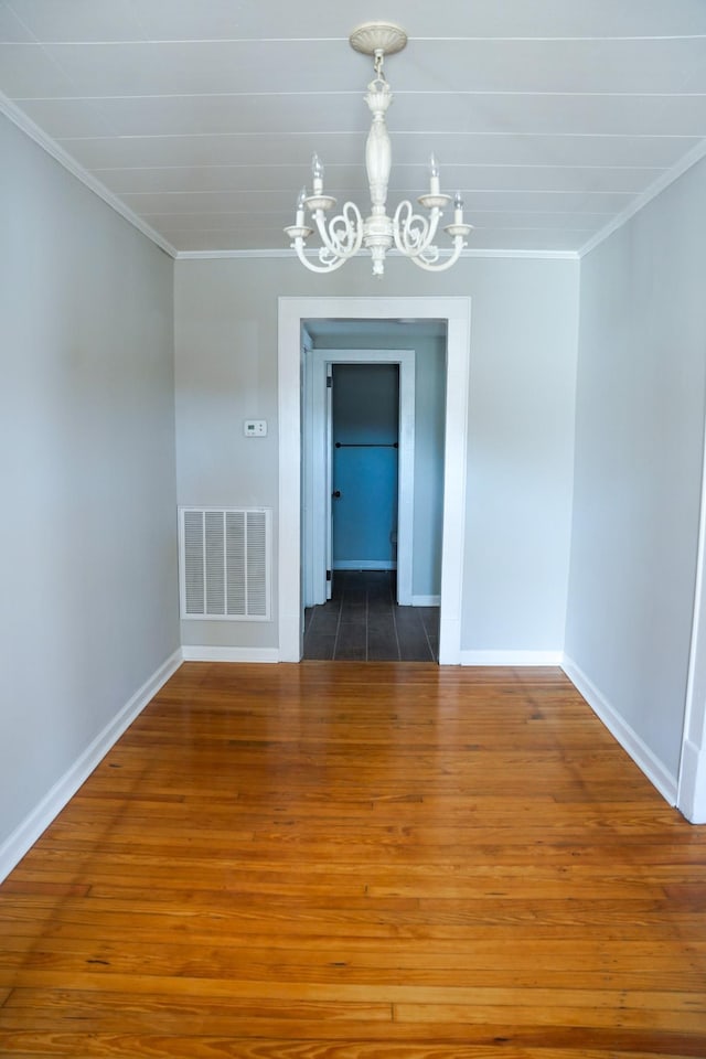 unfurnished dining area with ornamental molding, dark wood-type flooring, and an inviting chandelier