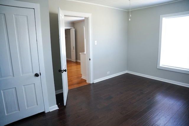 empty room with crown molding and dark hardwood / wood-style flooring