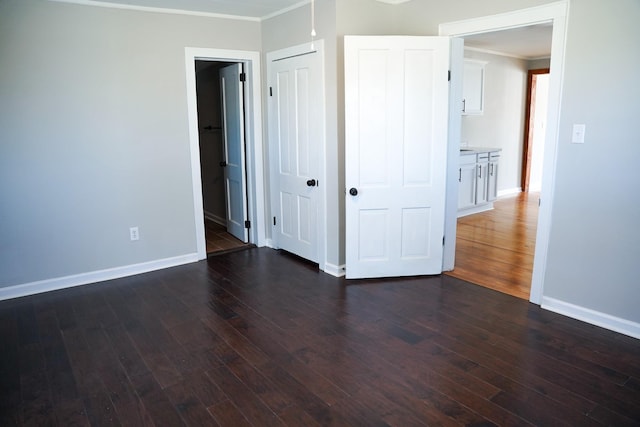 unfurnished bedroom featuring dark hardwood / wood-style flooring, ornamental molding, and a closet