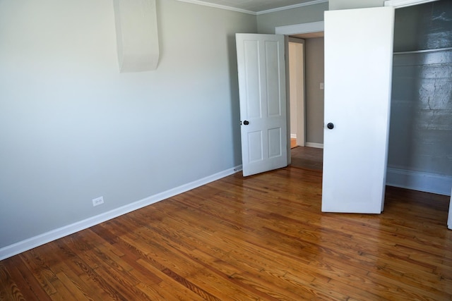 unfurnished bedroom with dark hardwood / wood-style flooring, ornamental molding, and a closet