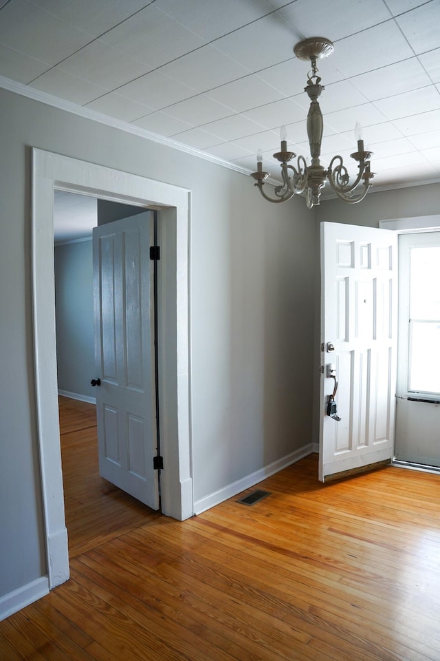 unfurnished dining area featuring hardwood / wood-style floors, crown molding, and a chandelier