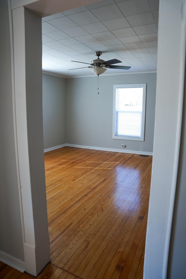 empty room with crown molding, wood-type flooring, and ceiling fan