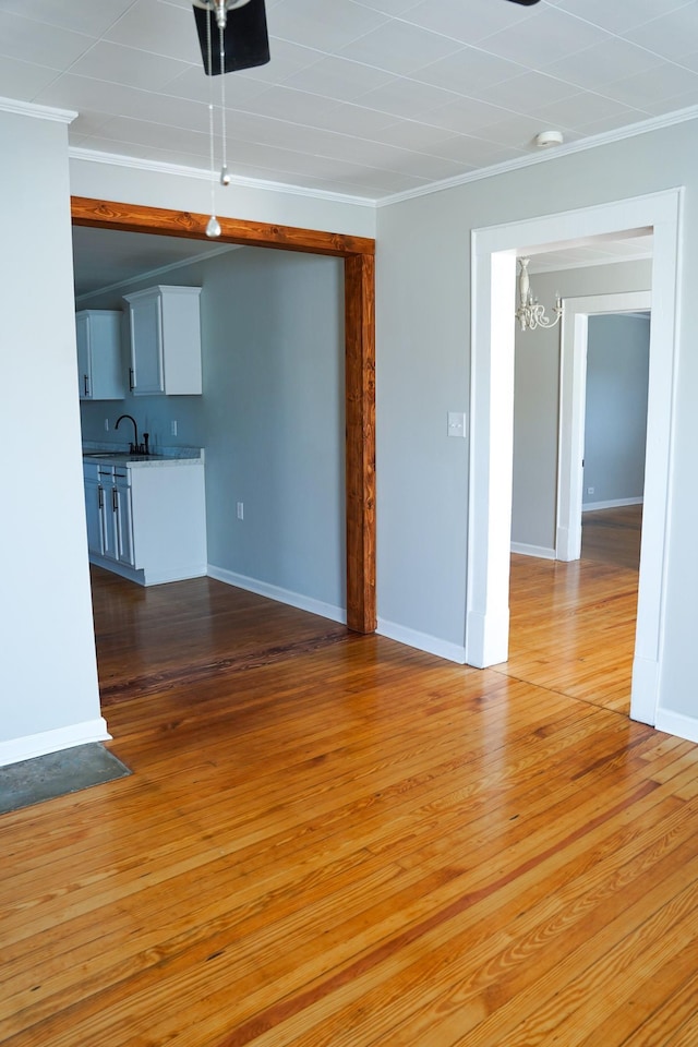 unfurnished living room featuring crown molding, an inviting chandelier, and light hardwood / wood-style floors