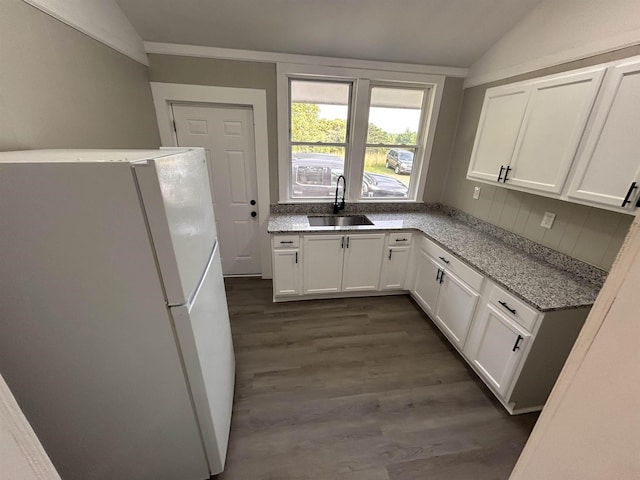 kitchen with white refrigerator, vaulted ceiling, sink, and white cabinets