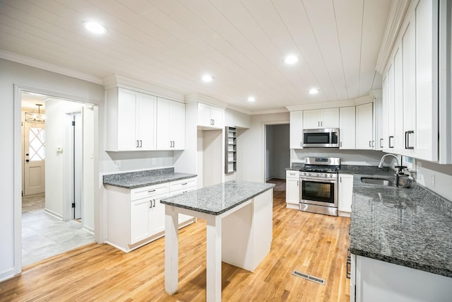 kitchen with white cabinetry, stainless steel appliances, sink, and a kitchen island