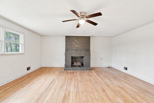 unfurnished living room featuring a brick fireplace, ornamental molding, light hardwood / wood-style floors, and a textured ceiling