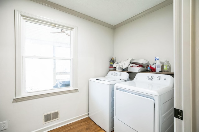 laundry room featuring hardwood / wood-style floors, crown molding, and washer and dryer