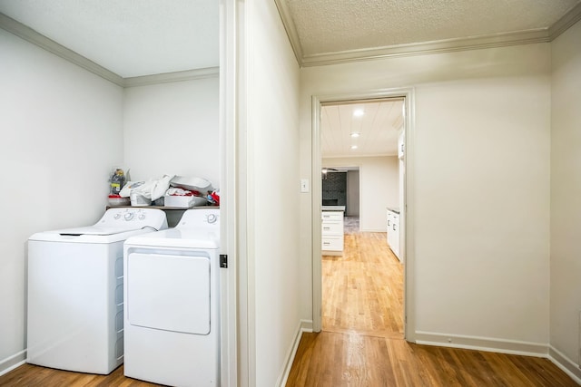 laundry room featuring crown molding, separate washer and dryer, hardwood / wood-style floors, and a textured ceiling