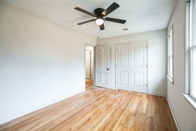 unfurnished bedroom featuring a closet, ceiling fan, a textured ceiling, and light hardwood / wood-style flooring