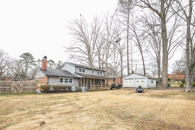 rear view of property featuring a yard, a garage, an outdoor structure, and covered porch