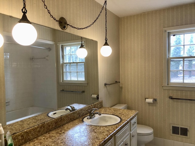 bathroom with a healthy amount of sunlight, toilet, and vanity