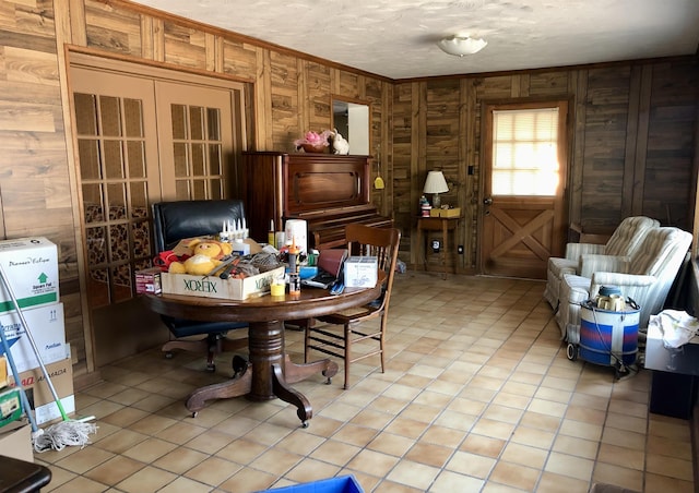 tiled dining space with crown molding, wooden walls, and a textured ceiling