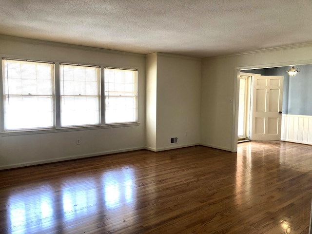 empty room featuring ornamental molding, dark hardwood / wood-style floors, and a textured ceiling