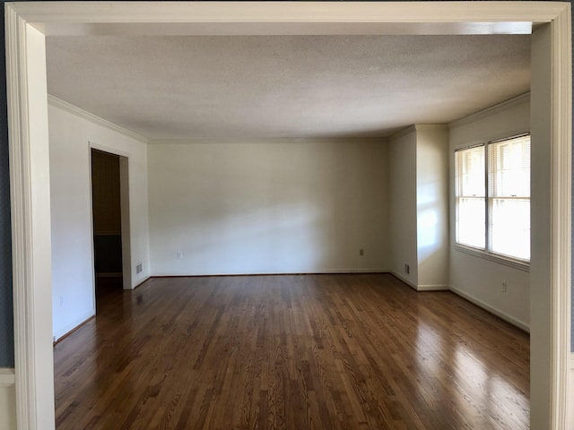 empty room featuring dark wood-type flooring, ornamental molding, and a textured ceiling