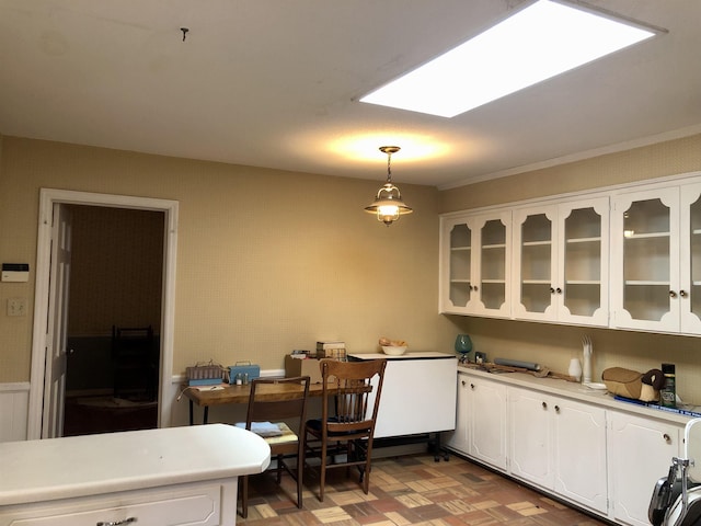 kitchen with white cabinetry, parquet floors, a skylight, and hanging light fixtures