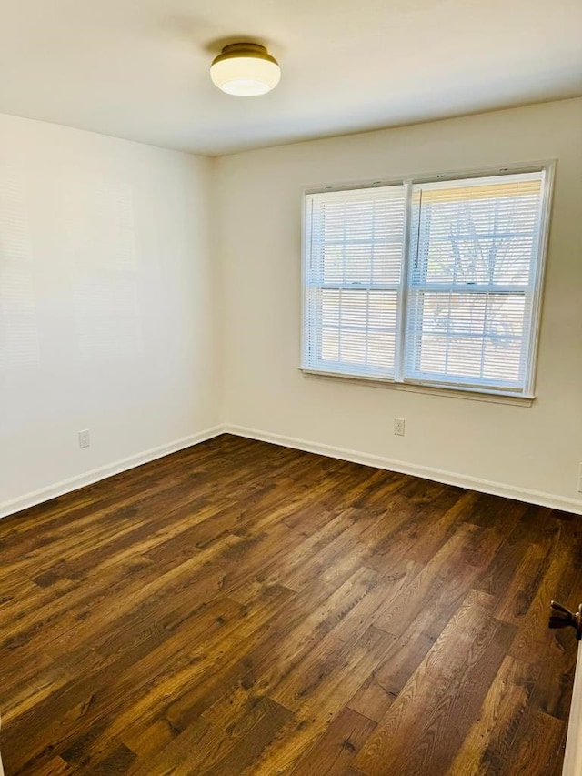 empty room with dark wood finished floors and baseboards