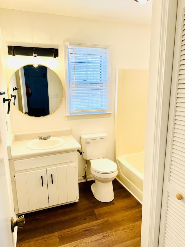 full bathroom featuring a tub to relax in, a closet, toilet, vanity, and wood finished floors