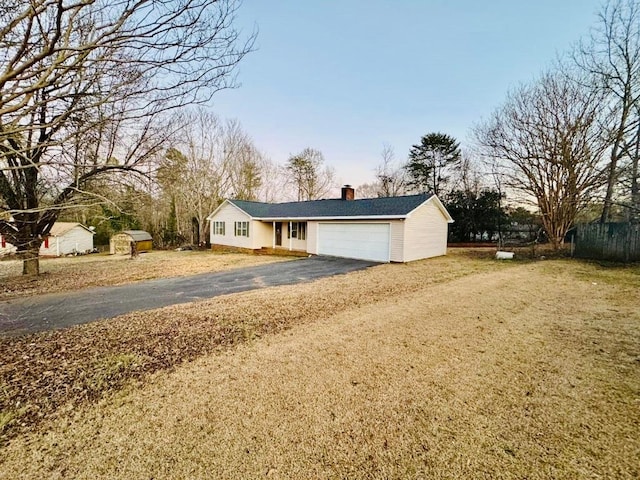 ranch-style house featuring aphalt driveway, a chimney, and a garage